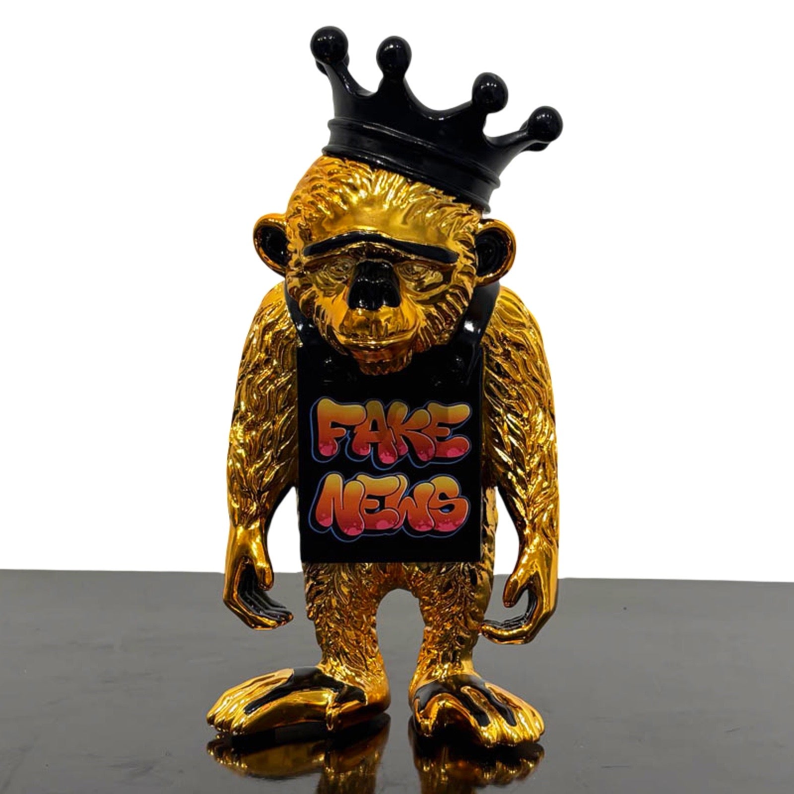 Sculpture of an golden monkey with black Fake News sign and crown