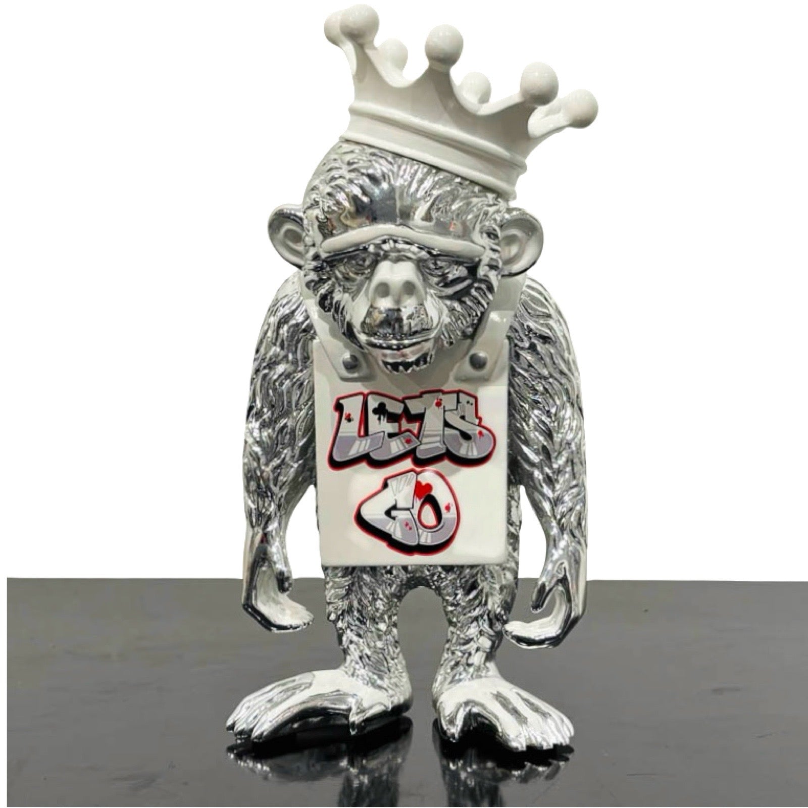 Sculpture of an silver monkey with white Lets Go sign and crown